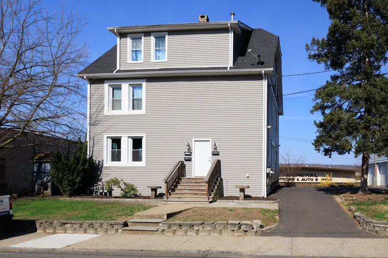 Exterior front of a two-and-a-half story gray colonial home with front entry stairs
