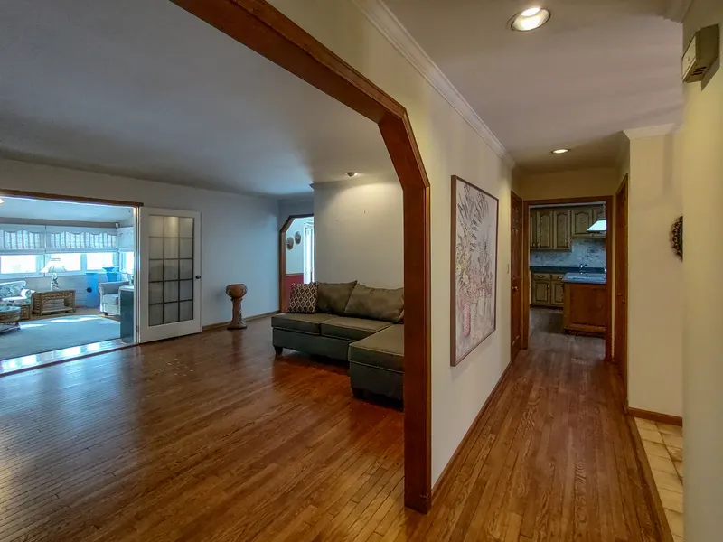 Open-concept main floor with a sectional sofa, a wood-framed archway, and the kitchen visible beyond